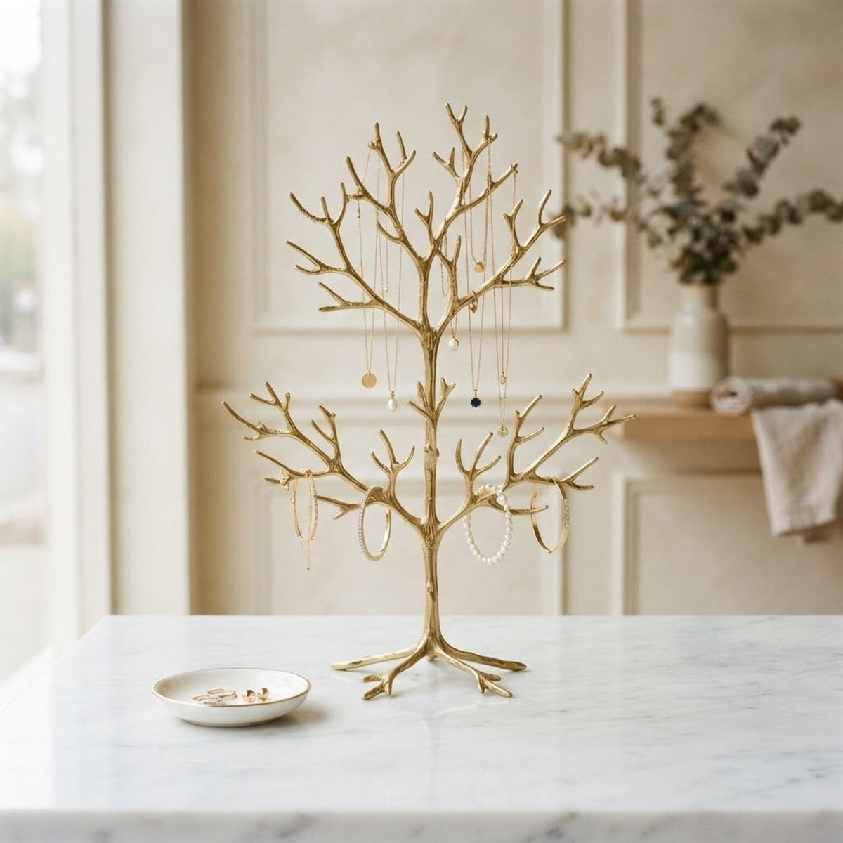 Arbre à bijoux doré avec colliers suspendus sur une console en marbre