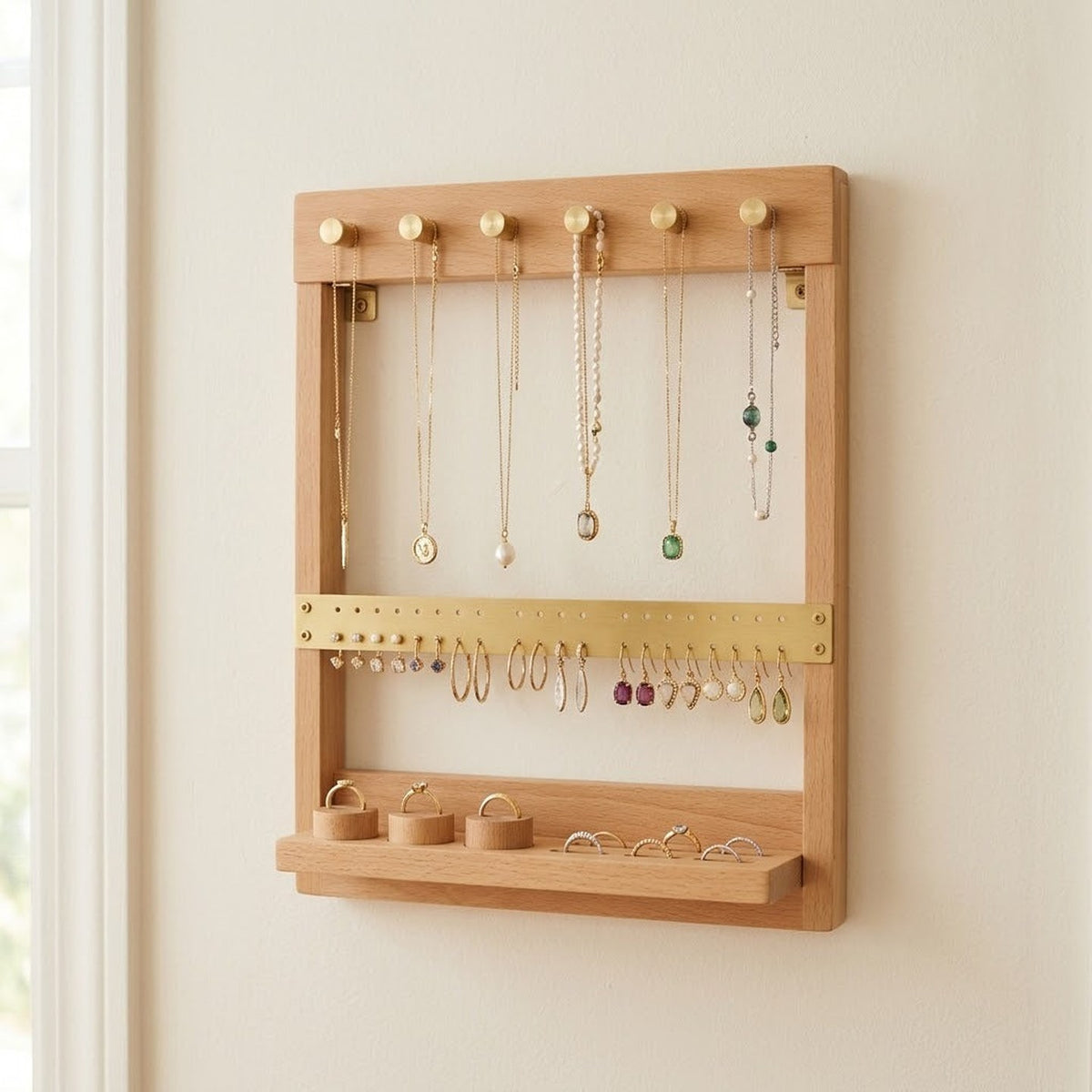 Porte-bijoux mural en bois clair avec colliers, boucles d'oreilles et bagues