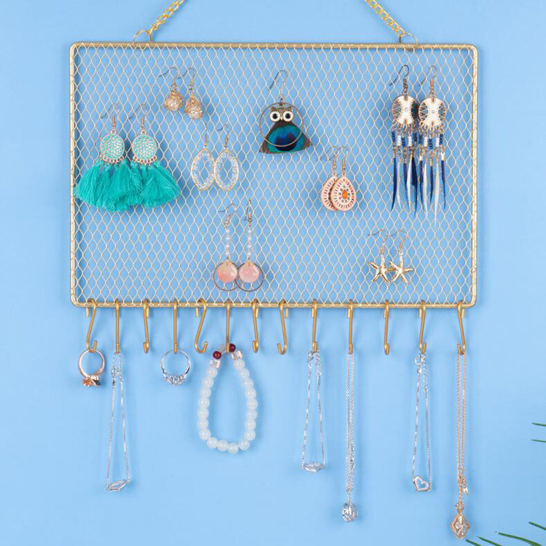 Présentoir bijoux mural à grille dorée – format horizontal sur fond bleu