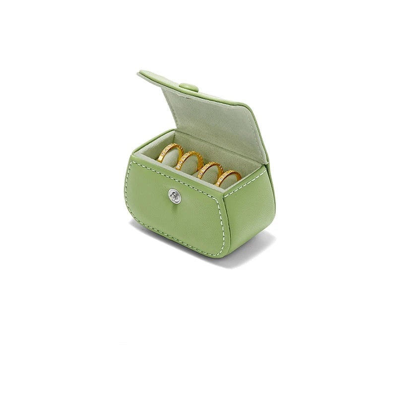 Boîte à bague de voyage en cuir vert – vue sur fond blanc avec quatre bagues