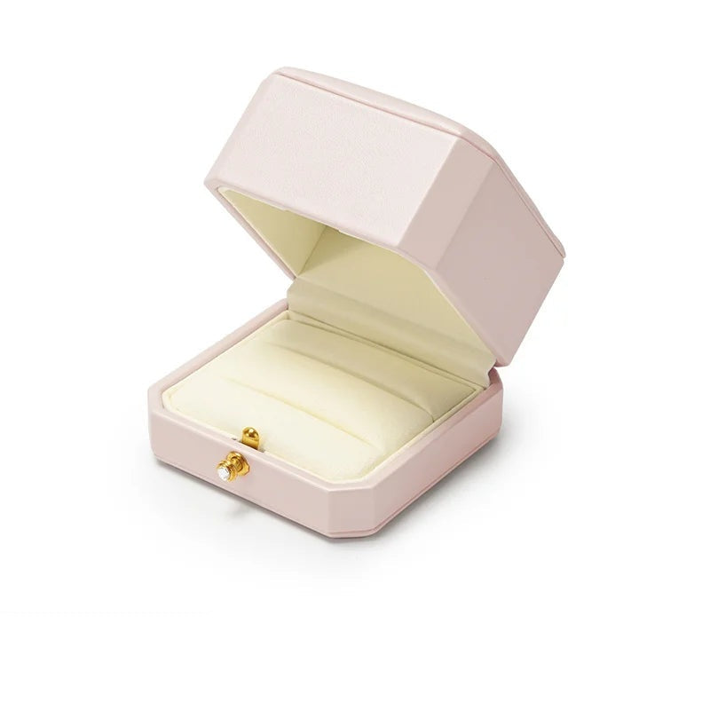 Écrin à bague rose – ouvert sur le coussin crème, fond blanc