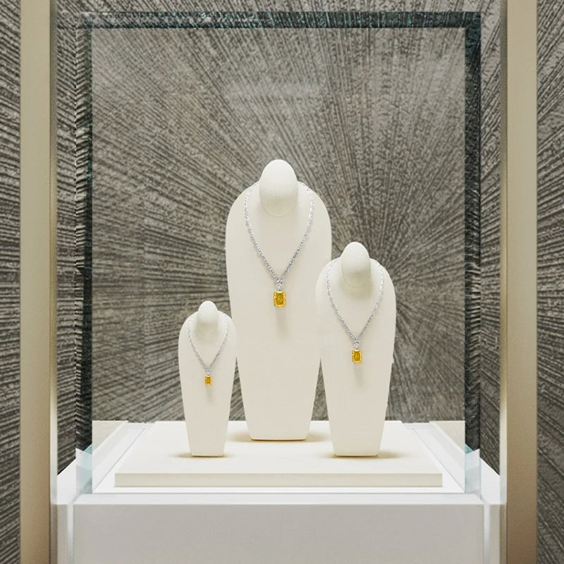 Buste collier microfibre – trois bustes beige dans une vitrine en verre