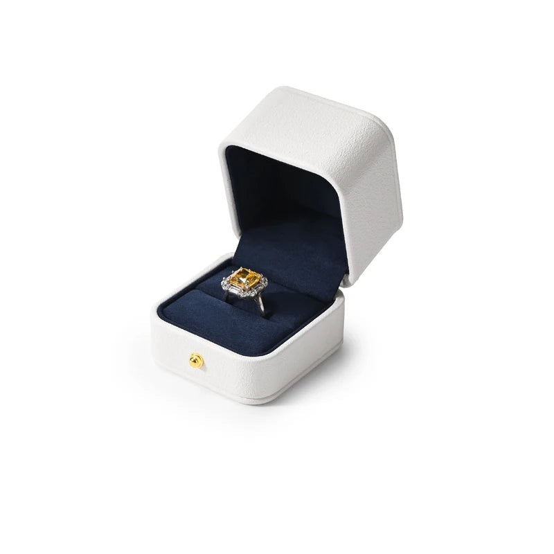 Écrin blanc – écrin à bague ouvert avec une bague à pierre jaune