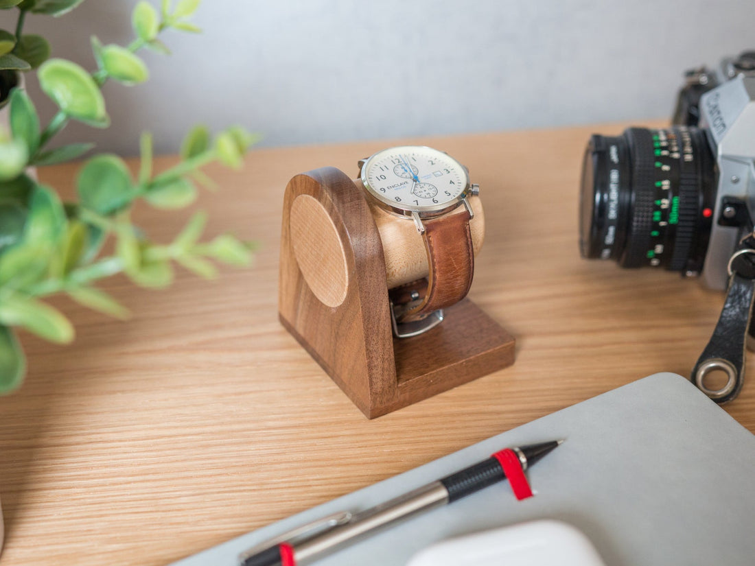 Porte montre homme bois massif – version brune en situation sur un bureau, avec carnet et appareil photo